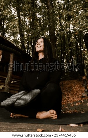 Girl posing and holding hands on Sadhu boards in autumn in the forest. Yoga and nailing concept
