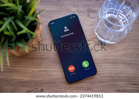 phone with incoming call on screen background of wooden table with in office Royalty-Free Stock Photo #2374419813
