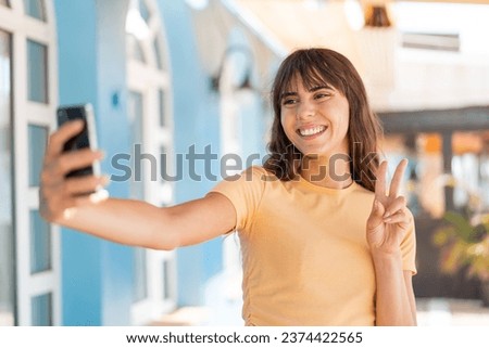 Young woman at outdoors making a selfie with mobile phone