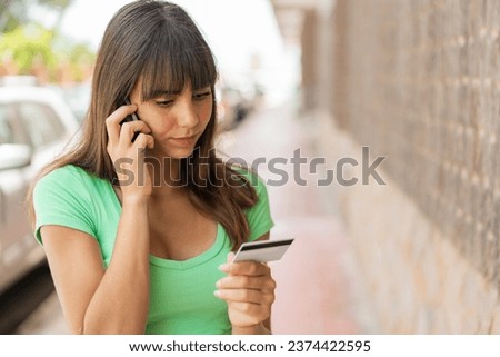 Young woman at outdoors buying with the mobile with a credit card