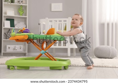 Cute baby making first steps with toy walker at home