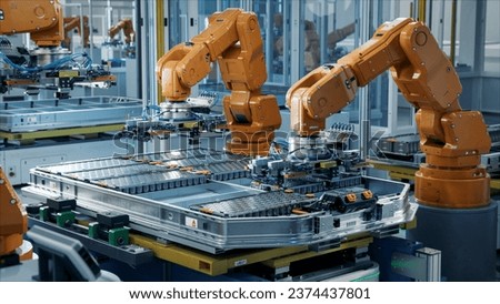 Orange Industrial Robot Arms Assemble EV Battery Pack on Automated Production Line. Row of Advanced Robotic Arms inside Automotive Plant Assemble Batteries. Modern Electric Car Smart Factory.