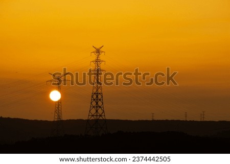 Sun disk at sunset. silhouette of high voltage line poles in orange sunset colors. Istanbul's energy transmission lines. Horizontal photo. No people, nobody. Natural and traditional energy sources.