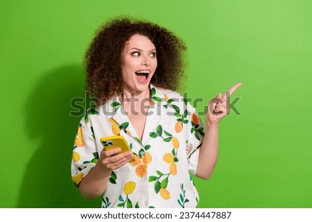 Photo of excited funky girl dressed print shirt texting modern gadget showing empty space isolated green color background