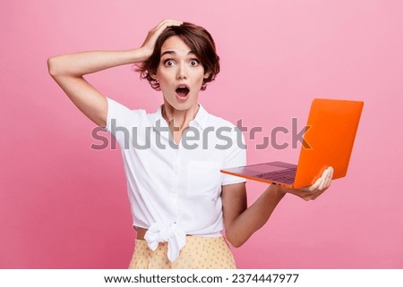 Photo of young girl staring speechless at you holding computer touching head because forgot her password isolated on pink color background