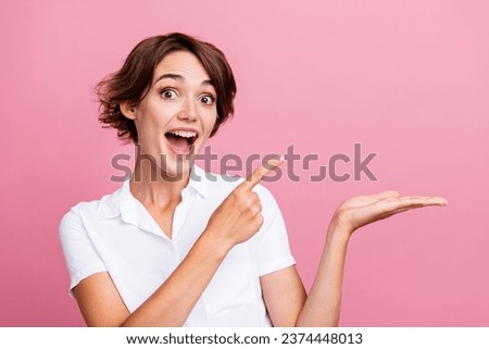 Portrait of crazy girl with short hairstyle wear stylish blouse directing at promo on arm empty space isolated on pink color background