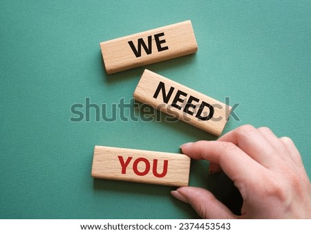 We need you symbol. Concept words We need you on wooden blocks. Beautiful grey green background. Businessman hand. Business and We need you concept. Copy space.