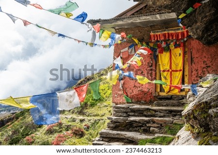 Small Buddhist monastery decorated with multicolored Tibetan prayer flags with mantras on Kothe - Thangnak climbing Mera peak route in Makalu Barun National Park. Peaceful and sacred place photo. Royalty-Free Stock Photo #2374463213