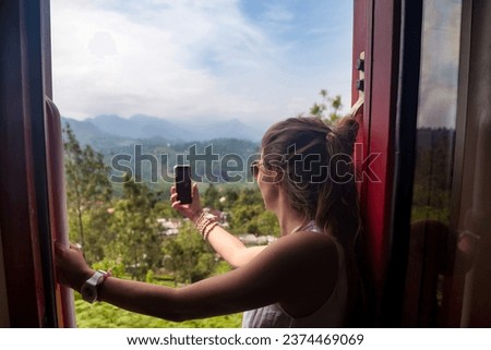 Lovely lady tourist travel by train to in Sri Lanka, takes selfie photo. Perfect traveler woman enjoying extreme sri lankan train ride in tropic. Tropical summer vacation concept. Copy ad text space