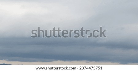 Autumn brings overcast skies adorned with gray stratus clouds, hinting at impending rain. This full-screen view provides ample space for text or design elements, making it perfect for various projects Royalty-Free Stock Photo #2374475751