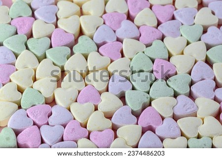 small heart-shaped candies on a pink background