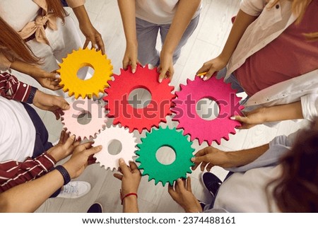 Group of school, college or university students working on project all together. Team of young people holding colorful green, pink, red, yellow gear cog wheels. Top view. Education, teamwork concept Royalty-Free Stock Photo #2374488161