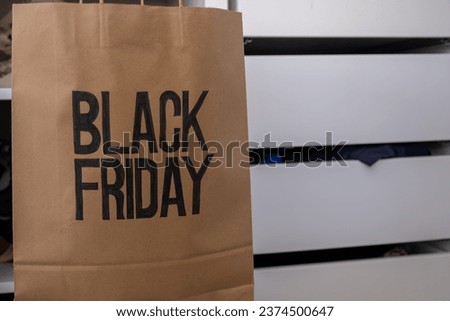 Black friday shopping bag with clothes with clothes hanger in front of drawers , also with mock up space