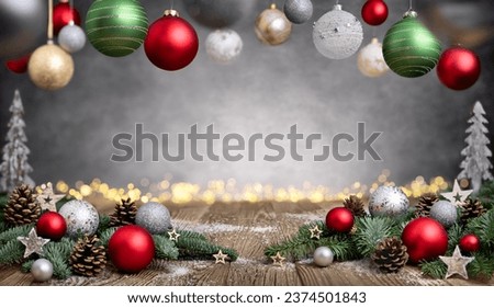 Christmas background with pretty decoration: ornaments arranged on rustic wood surface, bokeh lights and baubles frame an illuminated gray texture with vignetting