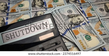 Shutdown of the US Government. A calculator with the word "shutdown" on the screen surrounded by 100 US dollar bills. Congress and the Senate. Suspension of work of state bodies, crisis, unpaid leave Royalty-Free Stock Photo #2374516497