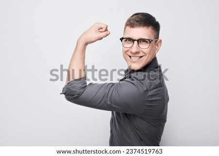 Portrait of confident young man showing biceps, demonstrating strength isolated on white studio background. Lucky winner concept