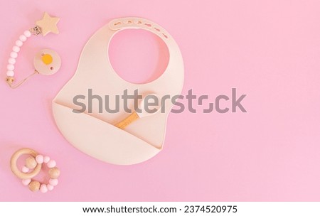 Flat lay with plate and bib for baby feeding, first baby solid food idea. Top view in pastel colors Royalty-Free Stock Photo #2374520975