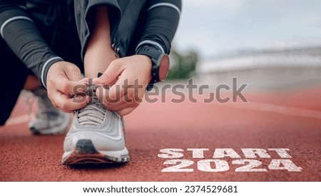 Athletes are getting ready to run on the track with text Start 2024 in New Year's start concept. Royalty-Free Stock Photo #2374529681