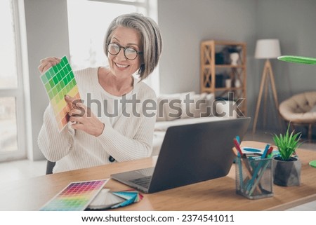 Photo of cheerful pretty senior lady architect dressed white cardigan showing client new design colors indoors house room
