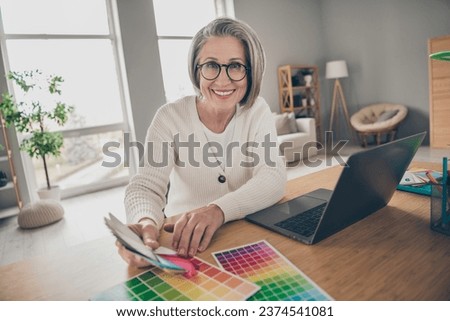 Photo of positive good mood senior lady dressed white cardigan showing new colors palette indoors house room