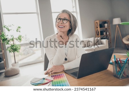 Photo of good mood dreamy senior lady architect dressed white cardigan thinking new design colors indoors house room