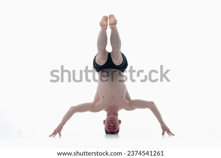 Headstand yoga asana, Ashtanga yoga  Side view of man wearing sportswear doing Yoga exercise against white background.  Royalty-Free Stock Photo #2374541261