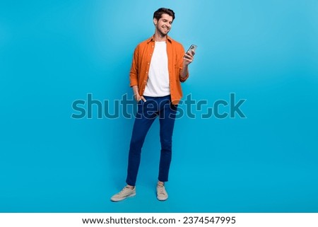 Full body photo of cheerful young man hold use smart phone chatting blogging isolated on blue color background Royalty-Free Stock Photo #2374547995