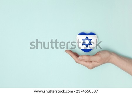 Heart with print of Israel flag in female hands. Flat lay. Copy space.