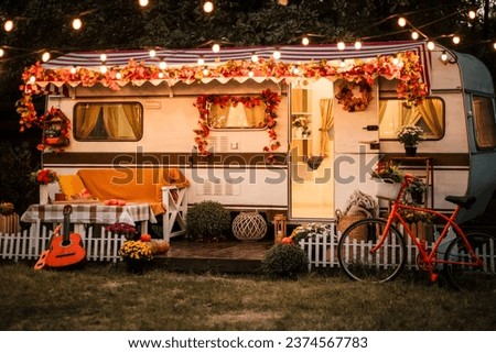 Camping season is autumn. Photo studio. Trailer against the backdrop of the forest. the lights are glowing, the hay is near the trailer, the sun is shining