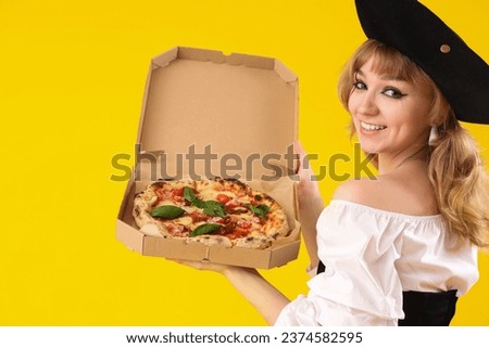 Young woman dressed for Halloween as pirate with tasty pizza on yellow background