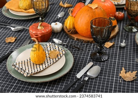 Beautiful table setting with autumn leaves and pumpkins in dining room, closeup