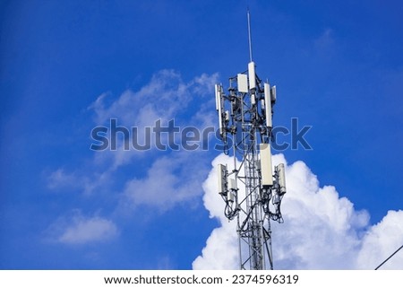 A tall communications antenna with clouds floating behind it. Royalty-Free Stock Photo #2374596319
