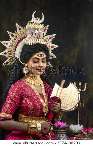 Portrait of beautiful Indian girl of Durga Idol Agomoni Concept Indoor Photo wearing traditional Indian saree, gold jewellery, and bangles. Maa Durga agomoni shoot concept.Indian culture durga puja.