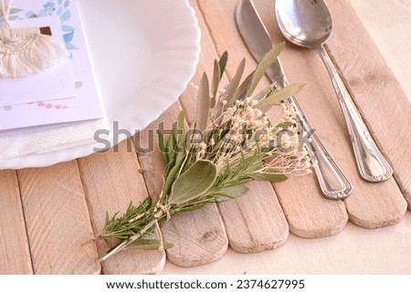 Wedding place setting table decoration small herbal bouquet olive leaves rosemary white flowers guest gift on plate macrame with cinnamon stick, rustic vintage boho style party, ceremony, event Royalty-Free Stock Photo #2374627995
