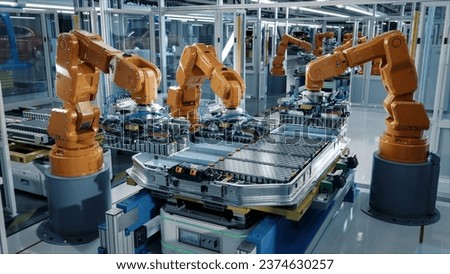 Advanced Orange Industrial Robot Arms Assemble EV Battery Pack on Automated Production Line. Row of Robotic Arms inside Automotive Plant Assemble Batteries. Modern Electric Car Smart Factory. Royalty-Free Stock Photo #2374630257