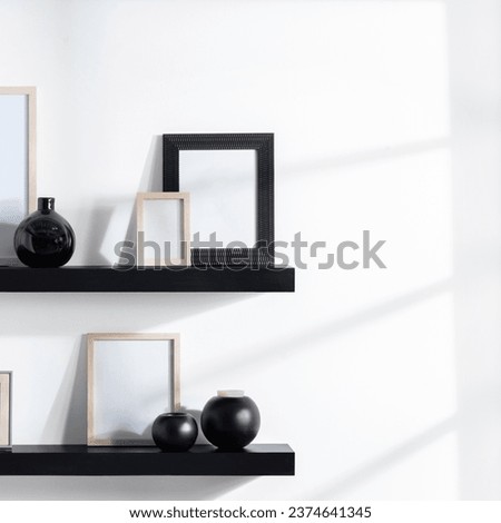 Minimalist Design, Black Floating Shelves with Assorted Picture Frames Mockup, Natural Wood  Textured Black. Paired with Sleek Ceramic Vases, Shadows on Bright White Wall Artistry. Copy Space
