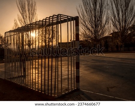 Capture the essence of city life with our stunning abstract photograph of a street soccer goal bathed in the warm, golden light of a sunrise. This image exudes the energy and vibrancy of urban culture
