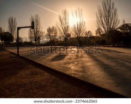 Elevate your creative projects with our stunning abstract urban park photo, featuring a basketball court bathed in the warm, orange hues of a sunrise. Perfect for stock agencies.