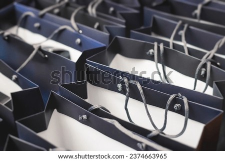 Corporate gifts and souvenirs for company employees, gift bag package for conference participants before start, presentation of corporate gifts, gift giving at office work, dark blue paper bag bunch Royalty-Free Stock Photo #2374663965