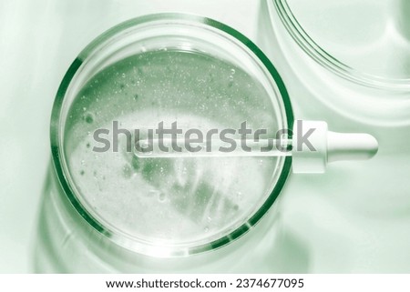 Liquid pipette serum emerald green gel on light berry colored mirror background Royalty-Free Stock Photo #2374677095