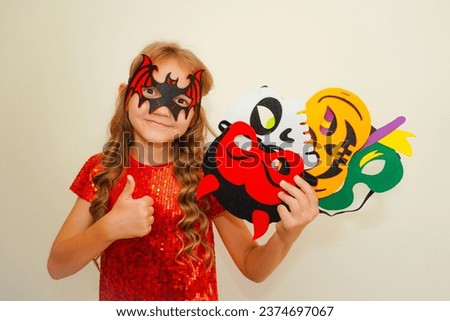 Halloween. Child in Halloween carnival mask. The child made handmade felt masks for Halloween. Kid in a bat costume. Girl prepared for Halloween celebration. Bat, pumpkin, witch, skull and devil masks