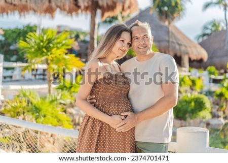 A happy, mature couple over 40, enjoying a leisurely walk in a park, their joy evident as they embrace the journey of pregnancy later in life Royalty-Free Stock Photo #2374701471
