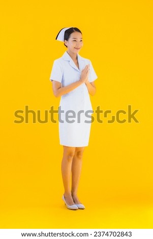 Portrait beautiful young asian thai nurse sawasdee or say hello in Thai on yellow isolated background