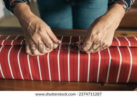 Hands wrapping a gift in red and white striped paper