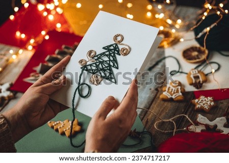 Process of creation of handmade Christmas card with wool thread embroidering on the craft recycled paper. Sustainable lifestyle, zero waste, personal gift. Family time, leisure activity, hobby Royalty-Free Stock Photo #2374717217
