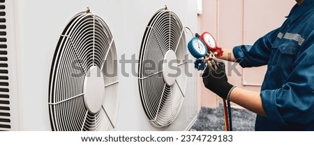 Heat and Air Conditioning, HVAC system service technician using measuring manifold gauge checking refrigerant and filling industrial air conditioner after duct cleaning maintenance outdoor compressor. Royalty-Free Stock Photo #2374729183