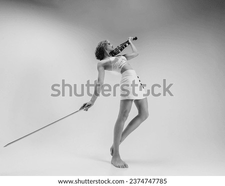 a young blonde female musician plays the violin with her eyes closed botton view