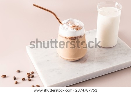 A large glass with a chocolate drink and chocolate wedges, a latte with foam on a marble white podium with a jug of milk. The perfect dessert