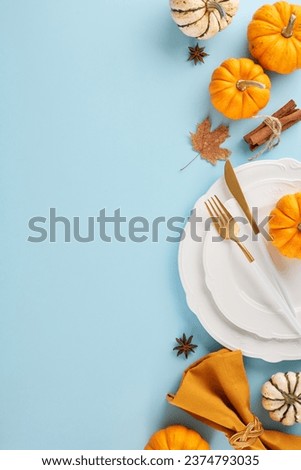 Design a table that makes Thanksgiving memorable. Top view vertical photo of pumpkins, plates, cutlery, cinnamon sticks, anise, fallen leaves on light blue background with promo zone