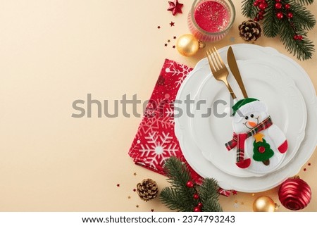 A picture-perfect Christmas dinner table. Top view photo of plates, cutlery, balls, napkin, candle, snowman, confetti, spruce twigs on beige background with advert area